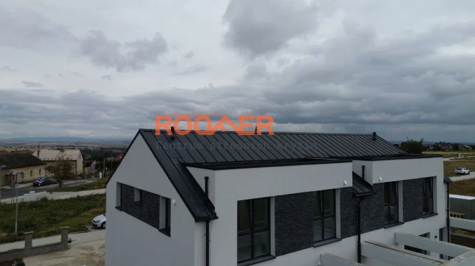 Stavba střechy na novém moderním dvojdomě (pokládka střešních panelů Klik Retro Plus RAL 7016 Mat) ve Slaný